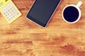 Top view of tablet, coffee cup and calculator over wooden textured table background. Royalty Free Stock Photo