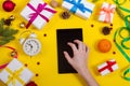 Top view with a tablet computer in the human hands on a table. Near the table with tablet computer christmas bell, gift balls and Royalty Free Stock Photo