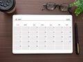 Top view, tablet showing May 2023 calendar app page and pen, tree, glasses, coffee cup on wooden table. Royalty Free Stock Photo