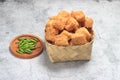 Photo Top View, tahu krispi or crispy Tofu and green chili at bamboo bowl, besek under brown abstract marble