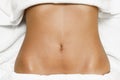 Top view of female abdomen laying on spa bed with white towels. Royalty Free Stock Photo