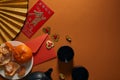 Top view of tangerines on plate, black tea set, fan with hieroglyphs, golden decorations and red envelope Royalty Free Stock Photo