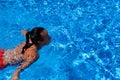 Top view of a tanned girl, female, model in a red swimsuit, swimming in the blue water of the pool Royalty Free Stock Photo