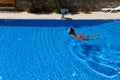 Top view of a tanned girl, female, model in a red swimsuit, swimming in the blue water of the pool Royalty Free Stock Photo