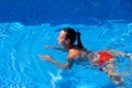 Top view of a tanned girl, female, model in a red swimsuit, swimming in the blue water of the pool Royalty Free Stock Photo