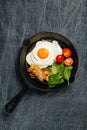 Top view of tasty bacon, egg, spinach and tomatoes with fry pan on grey linen cloth Royalty Free Stock Photo