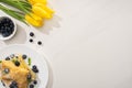Top view of tasty crepes with blueberries and mint on plate near yellow tulips Royalty Free Stock Photo