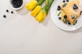 Top view of tasty crepes near bowl of blueberries and yellow tulips Royalty Free Stock Photo