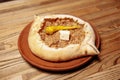Top view on tasty traditional Adjarian Khachapuri - open baked pie with meat and pepperyolk on wooden tray. Traditional georgian