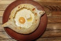 Top view on traditional Adjarian Khachapuri - open baked pie with melted salt cheese suluguni and egg yolk on wooden tray.