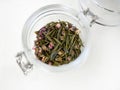 Top view of tea leaf blend flavor with dried red flowers petals, silver needle white rose tea, spring drink, organic in glass jar Royalty Free Stock Photo
