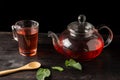 Top view of teapot and glass vase with rooibos tea, mint leaves, on wooden table