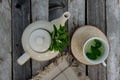 Top view of a teapot and tea cup with homemade mint tea on a wooden table.