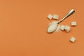 Top view of teaspoon and sugar on the orange surface.Empty space