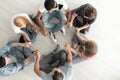 Top view on teenagers sitting in a circle and holding hands during group therapy Royalty Free Stock Photo