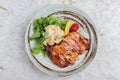 Top view of Teriyaki chicken served with potato salad, sliced lemon, totmato and green oak in round stone plate on washi. Royalty Free Stock Photo