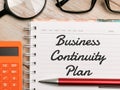 Top view text Business Continuity Plan written on note book with pen,calculator,magnifying glass and eye glasses on wooden backgro Royalty Free Stock Photo
