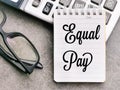 Top view text Equal Pay written on white paper note with calculator and eye glasses.