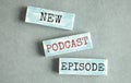 Top view of text NEW PODCAST EPISODE on wooden block podcasting