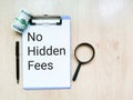 Top view text no hidden fees written on paper clipboard with a pen, magnifying glass and fake money. Royalty Free Stock Photo