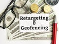 Top view text Retargeting and geofencing written on white paper note with compass,coins,fake money,pen and eye glasses. Royalty Free Stock Photo