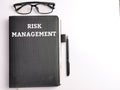 Top view text RISK MANAGEMENT on black book with pen and eye glasses isolated on white background. Royalty Free Stock Photo