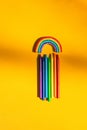Top view of textile rainbow and seven wax crayons in rainbow colors on bright yellow background Royalty Free Stock Photo