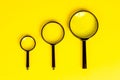 Top view of three black magnifying glass on light yellow background. Royalty Free Stock Photo