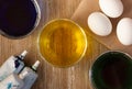 Top view of three bowls with colored water for colouring eggs in blue, yellow, green color and white eggs and food