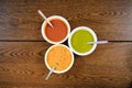 Top view of three bowls of colorful sauces put like a triangle on a wooden table