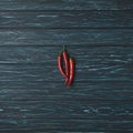 top view of three chili peppers on wooden table