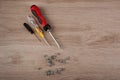Top view. Three different size and color screwdrivers and several screws lay on wooden table Royalty Free Stock Photo