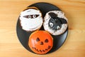 Top View of Three Different Types of Halloween Doughnuts on Black Plate Served on Wooden Table Royalty Free Stock Photo