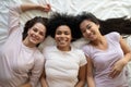 Top view three diverse girls best friends lying on bed