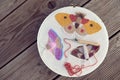 Top view of three embroidered multicolored butterflies on two-thread cloth in a hoop with punch needle and brick-red thread inside