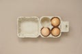 Top view of three fresh chicken eggs placed in paper egg carton on a brown background Royalty Free Stock Photo