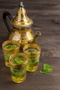 Top view of three glasses with tea and mint, decorated teapot, on dark wooden table, vertical Royalty Free Stock Photo