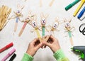 Top view of three handmade colorful funny bunnies made from wooden spoons in child hands.