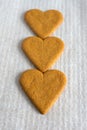 Top view of three heart shaped gingerbread cookies on white baking paper