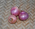 Top view of three medium sized red colored fresh onion gathered together on a wood background Royalty Free Stock Photo