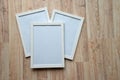 Three white blank frames on the wooden background. Mockup concept. Royalty Free Stock Photo