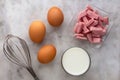 Top view of three raw brown egg, flour, milk and cutted sausages as ingredients of omelette on the marble surface Royalty Free Stock Photo