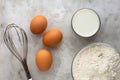 Top view of three raw brown egg, flour, milk and whisk as ingredients of batter or dough on the marble surface Royalty Free Stock Photo