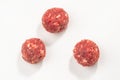 Top view on three raw meatballs on white background