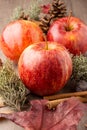 Top view of three red royal gala apples with cinnamon sticks and autumn leaves on wooden table Royalty Free Stock Photo