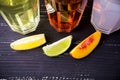 Top view of three slices of different fruit and glasess with coctails on a background. In a dark wooden table. Central focus. Royalty Free Stock Photo
