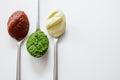 Top view of three spoons with different condiment on white background