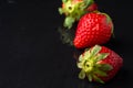 Top view of three strawberries on wet black stone slate, with reflection, horizontal Royalty Free Stock Photo