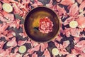 Top view tibetan singing bowl with floating inside in water pink peony flower. Burning candles and petals on the black stone