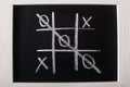 Top view of tic tac toe game on blackboard with crossed out row